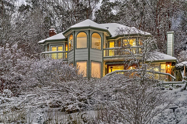 Victorian style lighted house framed in a snowy landscape, Bremerton, Washington, USA