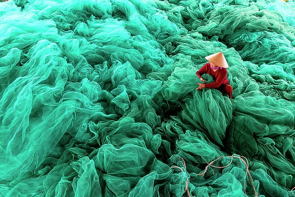 Vietnam, Cam Ranh, a woman mends green fishing nets