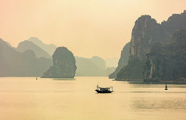 Vietnam, Quang Ninh Province, , Halong Bay, a fishing boat surrounded by Karst mountains