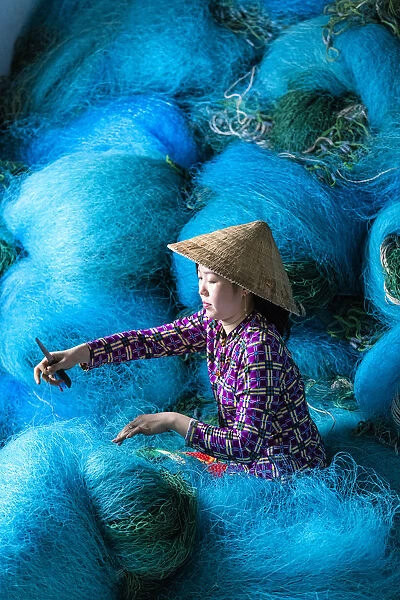 A Vietnamese woman mending blue fishing net, Mekong Delta, Vietnam