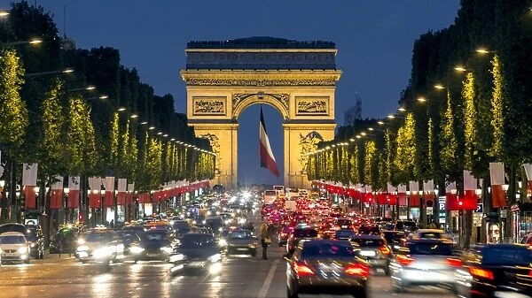 View down the Champs Elysees to the Arc de Triomphe, illuminated at dusk, Paris, France