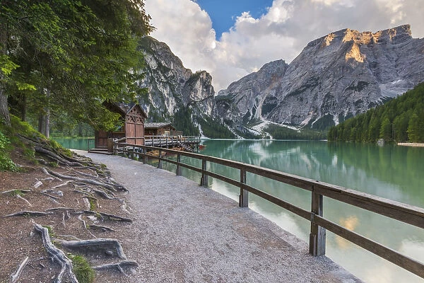 A view of Croda del Becco and footpath and house of boats from Braies lake at sunset