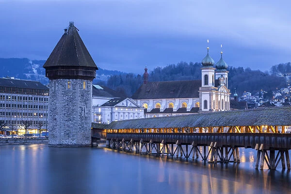 View of the Kapellbrucke bridge, the Jesuit Church and the Wasserturm at blue hour reflected on the Reuss river. Lucerne, canton of Lucerne, Switzerland