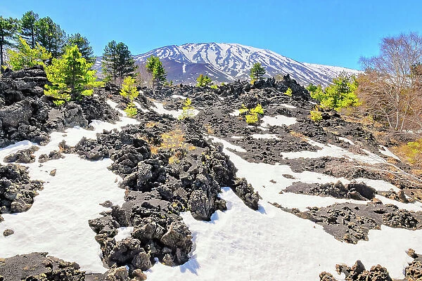View of lava fields and snow-capped peaks in the distance, Etna, Sicily, Italy