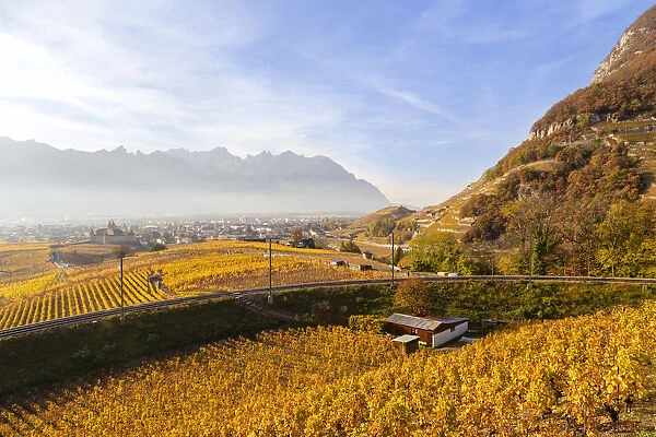 View of the medieval Aigle castle and the surrounding vineyards and railway in autumn