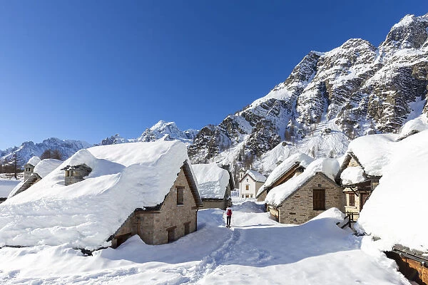 View of mountain huts and the church of the small town of Crampiolo in winter