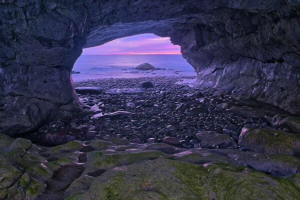 View of rocks along the Gulf of St. Lawrence at dusk as seen though the rock arch. Northern Peninsula. The Arches Provincial Park, Newfoundland & Labrador, Canada