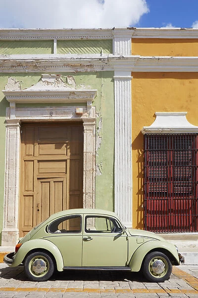 A vintage Volkswagen Bettle on a street of the historic center of Campeche with colorful houses in colonial architecture in the background, Yucatan, Mexico