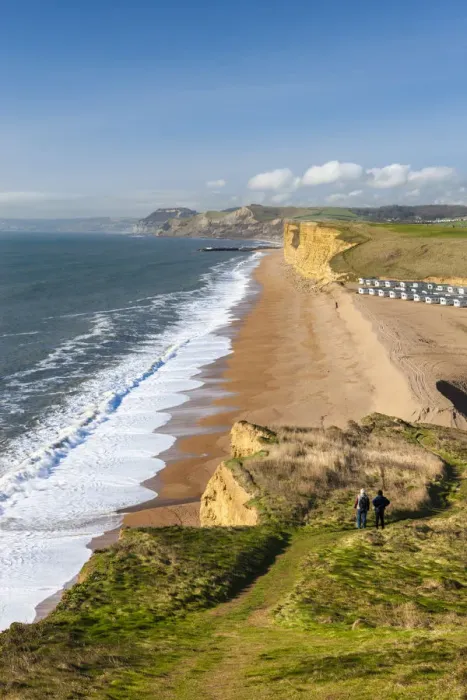 Framed Print : Two walkers enjoy the view along the beautiful vista from the cliffs of Burton Bradstock Framed Print : Two walkers enjoy the view along the beautiful vista from the cliffs of Burton Bradstock
