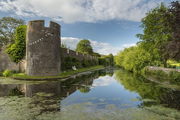 The walls and moat of Wells Bishops Palace on summer evening, Wells, Somerset