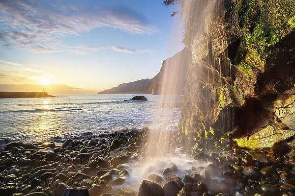 A waterfall in Seixal black sand beach during sunrise, Seixal, Porto Moniz, Madeira, Portugal