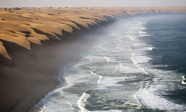The waves of the Atlantic Ocean crashing against the sandy wall of the Namib desert