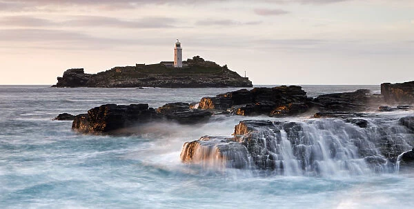 Waves crash over the rocks at Godrevy Point, looking out towards the lighthouse