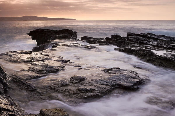 Waves crash over the rocks of Godrevy Point at sunset, Cornwall, England. Autumn