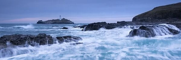 Waves crash around the rocks near Godrevy Lighthouse, Cornwall, England. Winter
