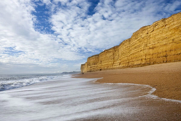 Waves wash clean Hive Beach backed by towering sandstone cliffs, Burton Bradstock