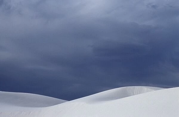 White sand dunes contrast against a stormy