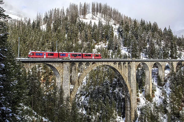 Wiesener Viaduct surrounded by snowy mountains and woods. Engadine. Canton of Graubunden