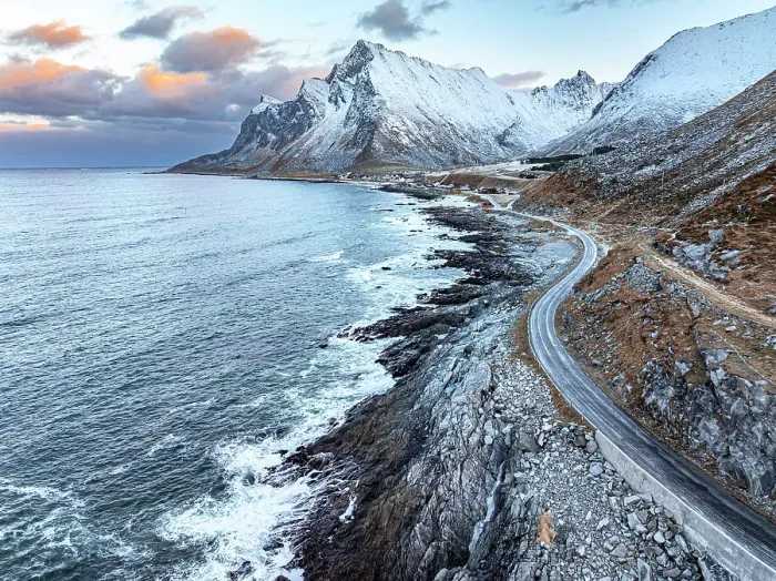 Framed Print : Empty winding road along the coastline with snowcapped mountains and Vikten village on background, Lofoten Islands, Norway Framed Print : Empty winding road along the coastline with snowcapped mountains and Vikten village on background, Lofoten Islands, Norway