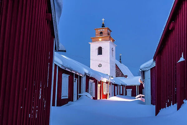 Winter dusk over the old bell tower and wood cottages covered with snow, Gammelstad Church Town, Lulea, Sweden