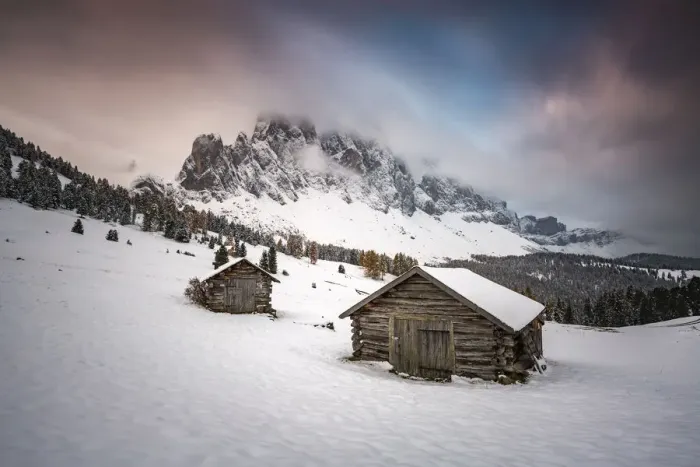 Framed Print : Winter scenery with two wooden lodges and Odle Dolomites covered in snow. Malga Gampen