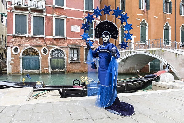 Woman in blue costume posing by canal during Carnival, Venice, Veneto, Italy