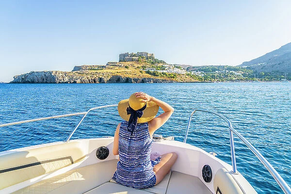 A woman on a boat looking at the Acropolis of Lindos, Lindos, Rhodes, Dodecanese Islands, Greece. (MR)