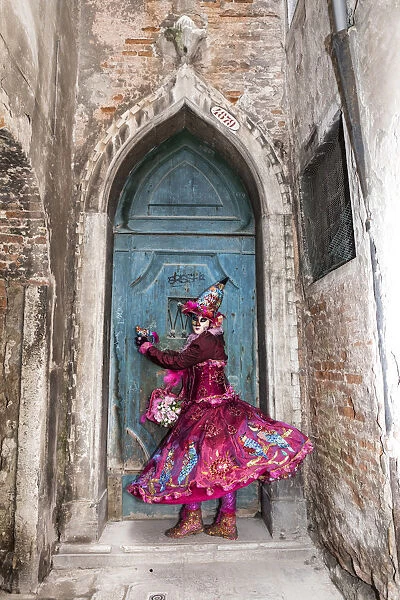 Woman in costume at blue door during Venice Carnival, Venice, Veneto, Italy