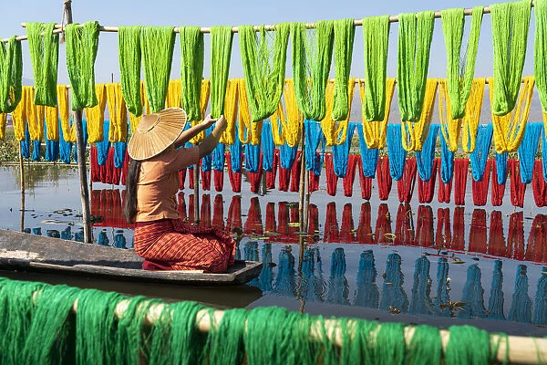 Woman hanging dyed yarn from a boat to dry in a traditional weaving village on Lake Inle