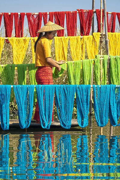 Woman hanging dyed yarn from a boat to dry in a traditional weaving village on Lake Inle