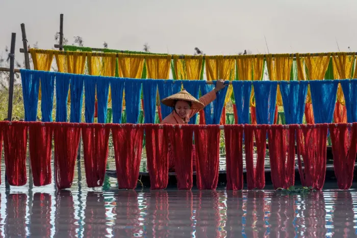 Framed Print : Woman hanging dyed yarn from a boat to dry in a traditional weaving village on Lake Inle Framed Print : Woman hanging dyed yarn from a boat to dry in a traditional weaving village on Lake Inle