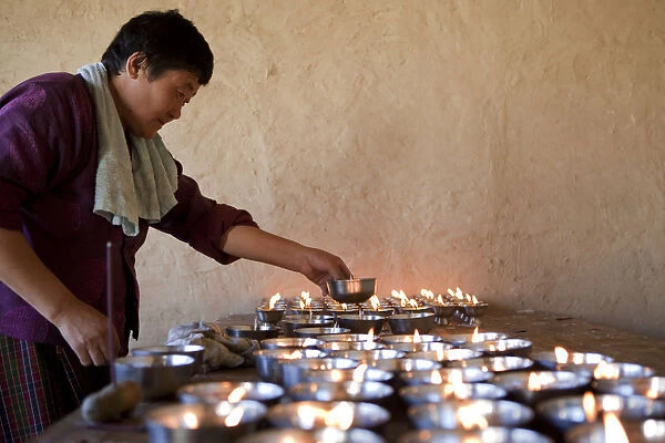 A woman lighting butter candles in Ura in the Bumthang Valley of Bhutan