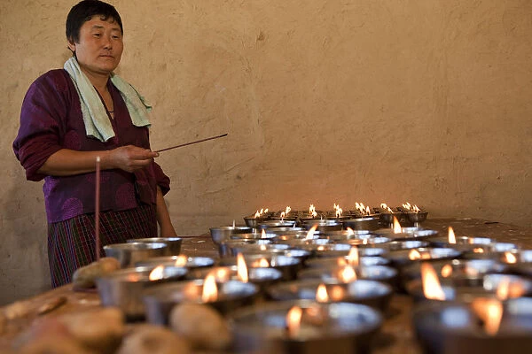 A woman lighting butter candles in Ura in the Bumthang Valley of Bhutan