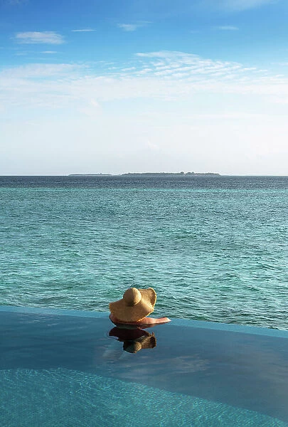 A woman looking at the ocean from the infinity pool, Baa Atoll, Maldives