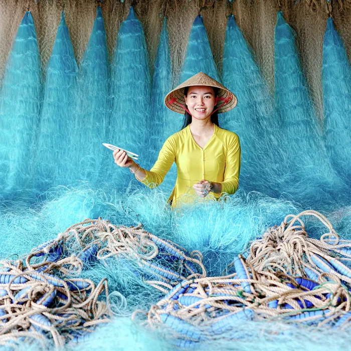 Framed Print : Woman repairing a blue fishing net, Vietnam. (MR) Framed Print : Woman repairing a blue fishing net, Vietnam. (MR)