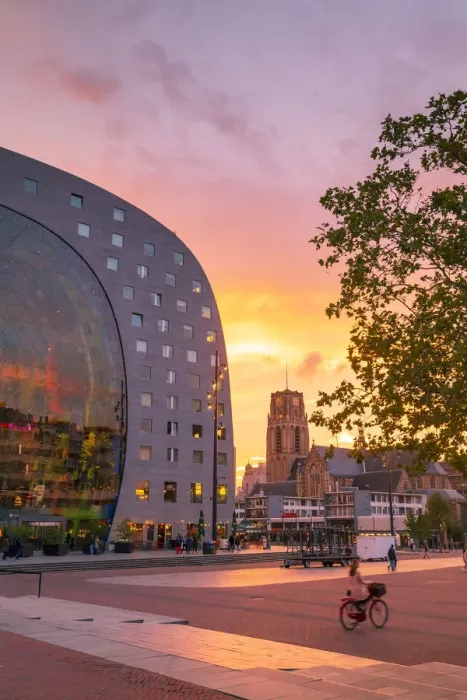 Framed Print : A woman riding a bike at sunset in front of the Market Hall in Rotterdam on a summer Framed Print : A woman riding a bike at sunset in front of the Market Hall in Rotterdam on a summer