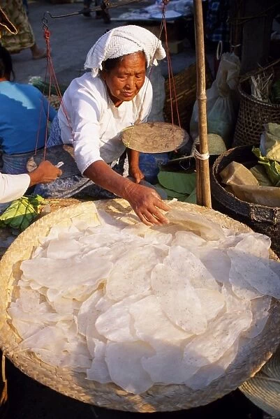 A woman sells rice pancakes from her stall at a street market