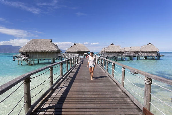 Woman walking on jetty of overwater bungalows of Sofitel Hotel, Moorea, Society Islands