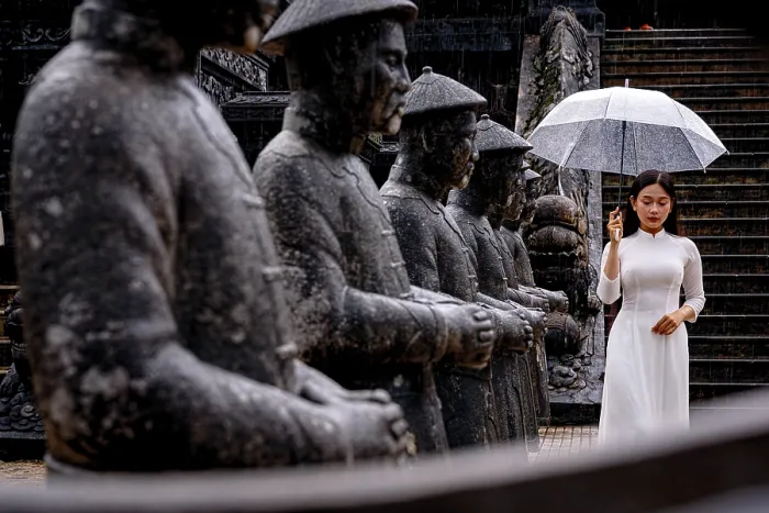 Framed Print : Woman in white ao dai by statues with umbrella, Khai Dinh Mausoleum, Hue, Vietnam. (MR)
