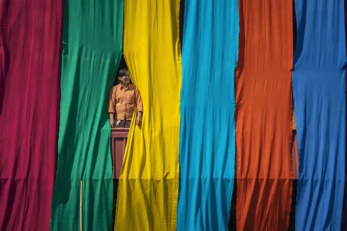 Framed Print : Woman in a window checking freshly dyed fabric hanging from bamboo poles to dry on a Framed Print : Woman in a window checking freshly dyed fabric hanging from bamboo poles to dry on a