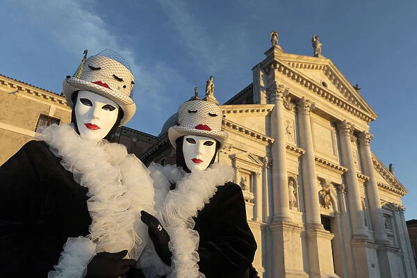 Two women pose in identical costumes during the Venice Carnival, San Giorgio Maggiore