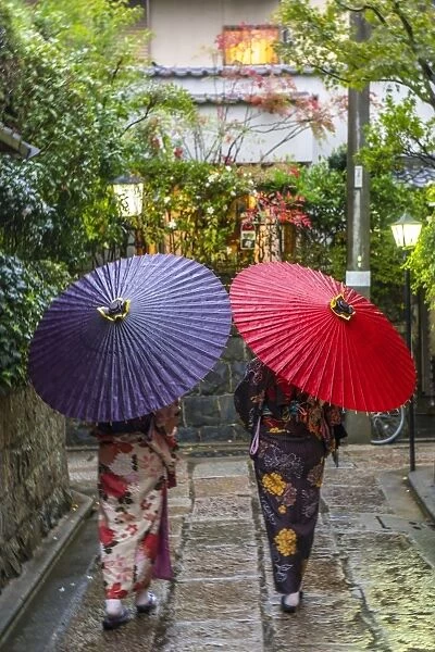 Women in traditional dress with umbrellas walking through Kyoto, Japan