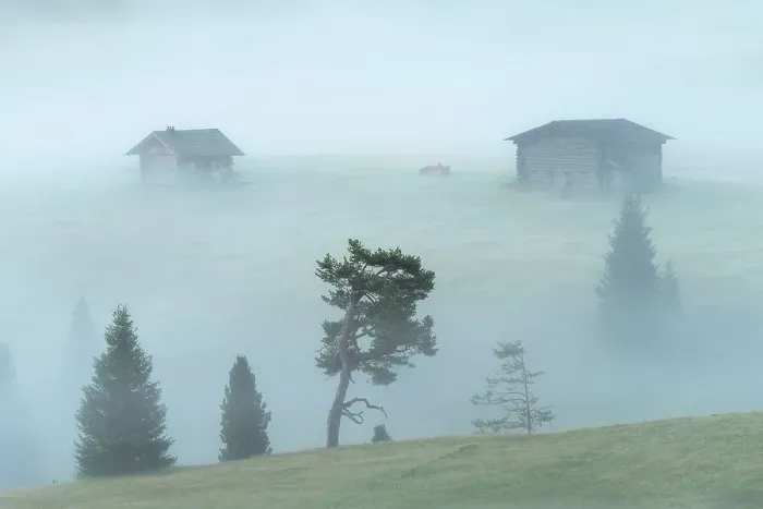Framed Print : Two wooden cabins appearing from the thick morning fog at the Alpe di Siusi. Dolomites, Italy