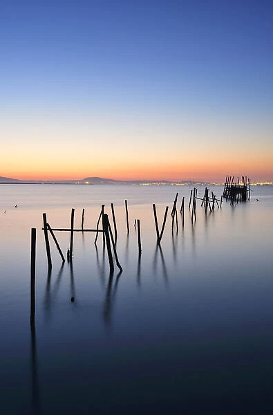 Wooden pillars piers, a palafite fishing harbour of Carrasqueira at dusk. Alentejo