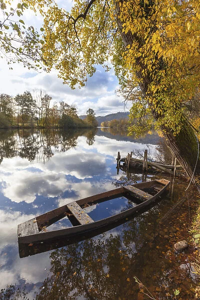 A wooden rowing boat in autumn on the Dordogne River, Correze, Nouvelle-Aquitaine