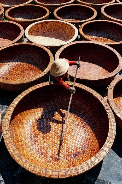 Framed Print : Worker applying oil to waterproof bamboo basket boats, Tuy An, Phu Yen province, Vietnam. (MR)
