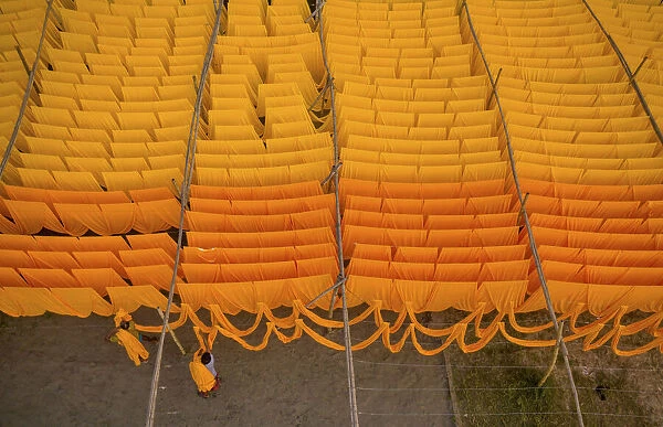 Workers hang thousands of metres of different coloured t-shirt fabrics to dry in