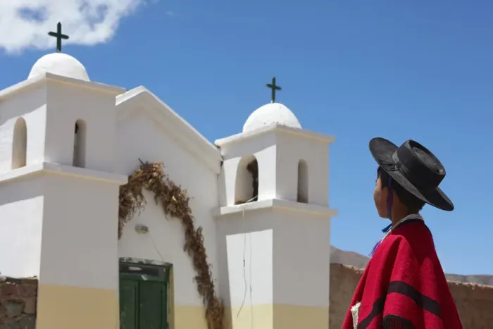 Framed Print : A young Aymara boy wearing traditional clothes stand in front of the small church of Framed Print : A young Aymara boy wearing traditional clothes stand in front of the small church of