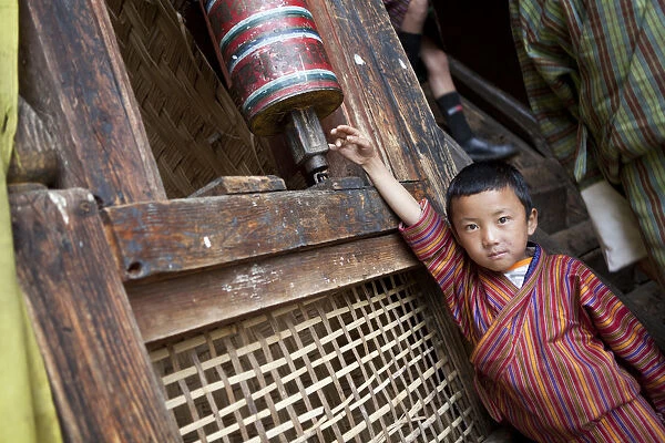 A young boy playing with a prayer wheel in the Thangbi Mani monastery in Bhutan