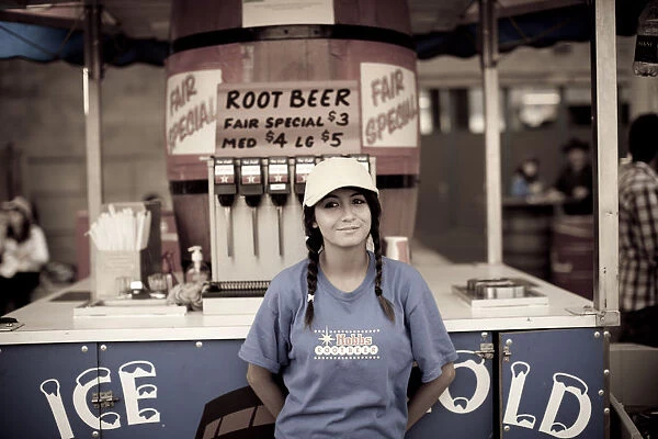 A young girl selling root beer at a midway concession at the Calgary Stampede, Canada